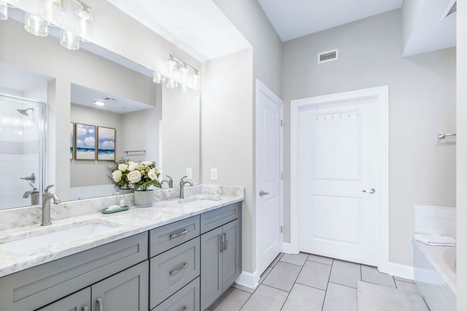 Elegant master bathroom featuring dual sinks, stylish fixtures, relaxing tub, and a spacious walk-in shower