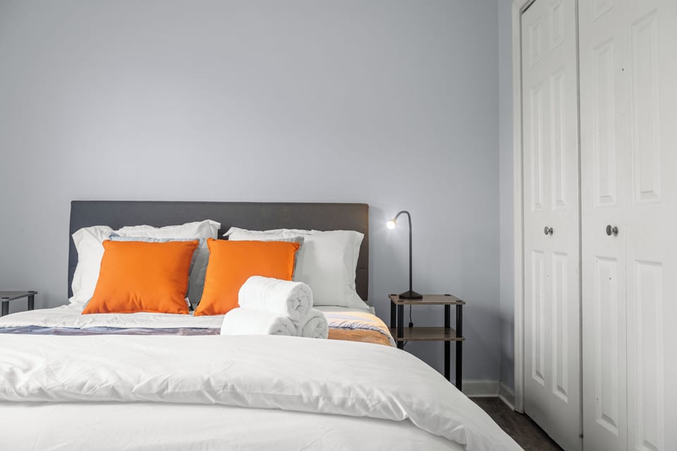 Bright and cozy bedroom with a plush queen bed, fresh linens, and cheerful accent pillows. Thoughtfully prepared with extra towels and bedside lighting—everything you need for a restful and comfortable stay.