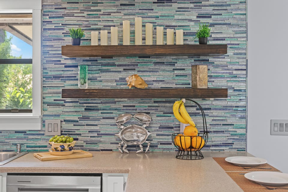 Thoughtfully designed kitchen corner with open wood shelving, vibrant backsplash, and fresh fruit ready to enjoy. A blend of style and function—perfect for morning coffee, light prep, or simply soaking in the cozy, curated atmosphere.