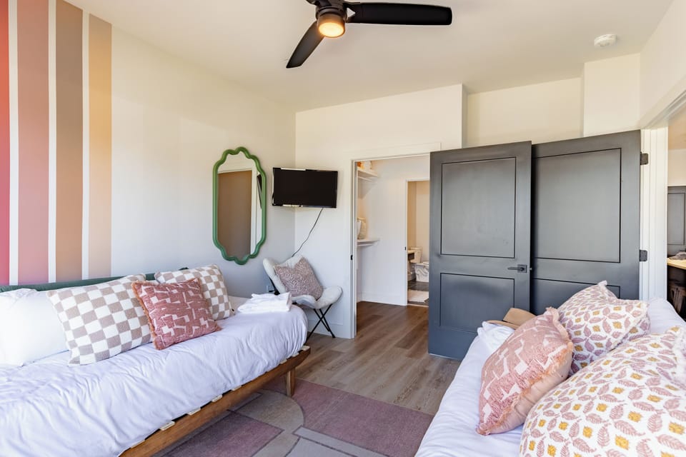 Bedroom 2 features two twin beds, a TV, and an ensuite bathroom. (Anthem)