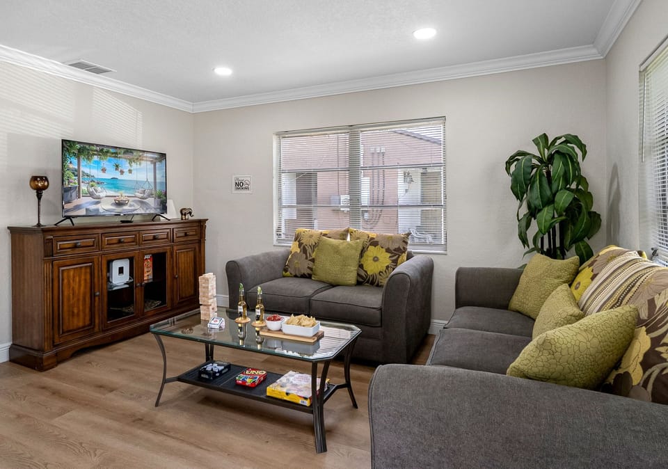 At the center of the room are two plush, soft grey couches, perfectly positioned to encourage relaxation, conversation, or a laid-back movie night.