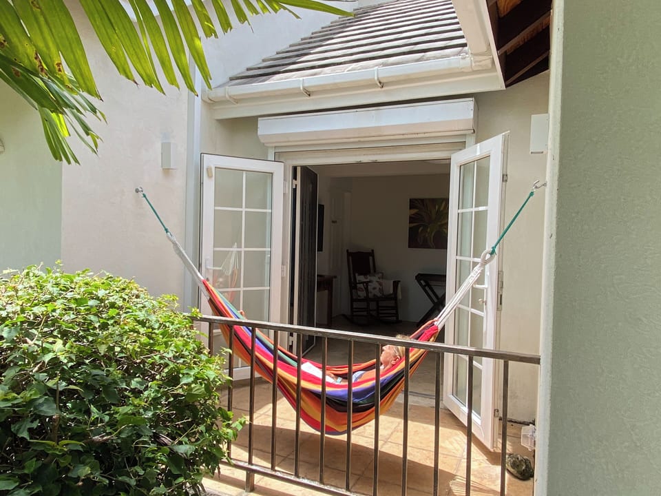 Private patio with hammock and tropical greenery.