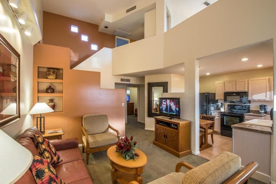 Experience the seamless flow of this chic two-story villa's living space, where the stylish decor and fireplace enhance the overall ambiance, leading to the inviting kitchen and beyond.