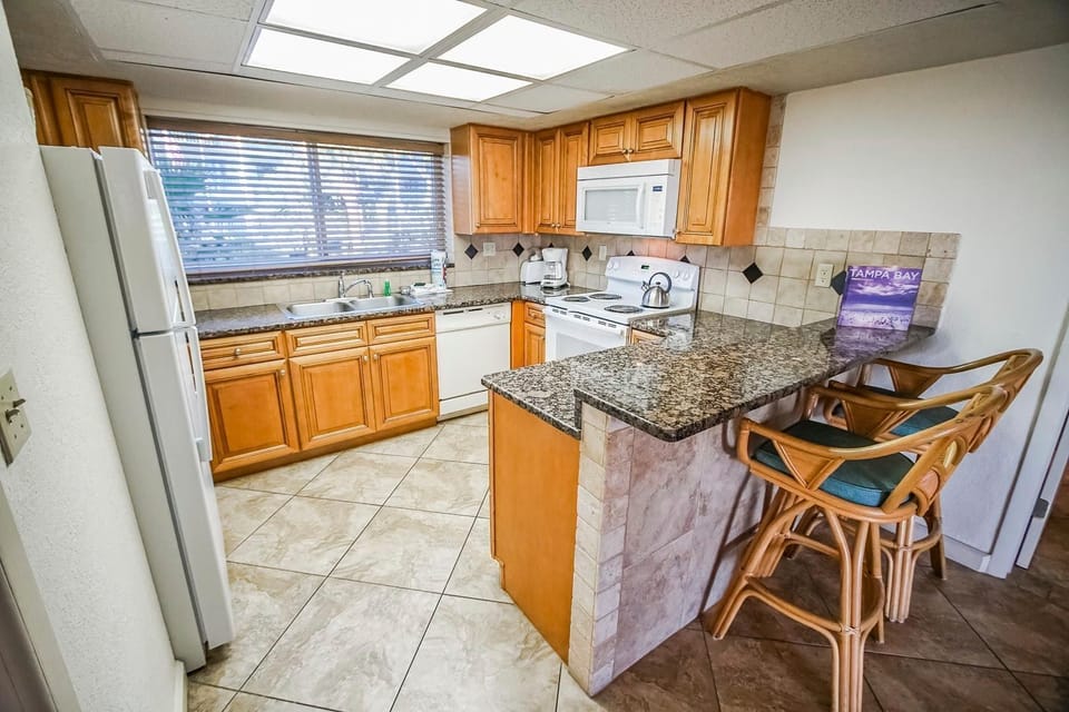 This modern kitchen boasts wooden cabinetry, granite countertops, and a full suite of appliances, perfect for all your cooking needs.