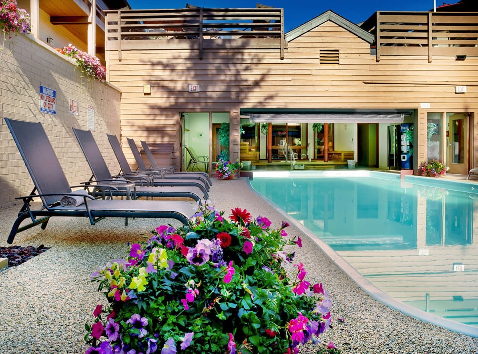 Relax by the beautifully landscaped shared pool area, featuring comfortable loungers and vibrant flower beds, perfect for enjoying warm alpine days.