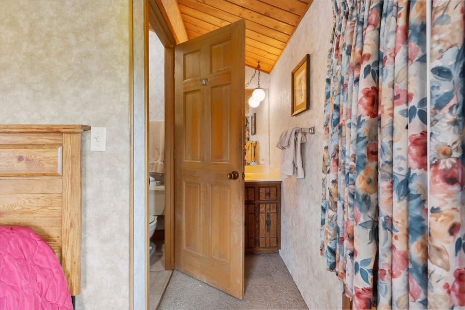 The cozy 3BR Chalet Cabin features comfortable sleeping spaces with warm wooden accents and easy access to a private bathroom.