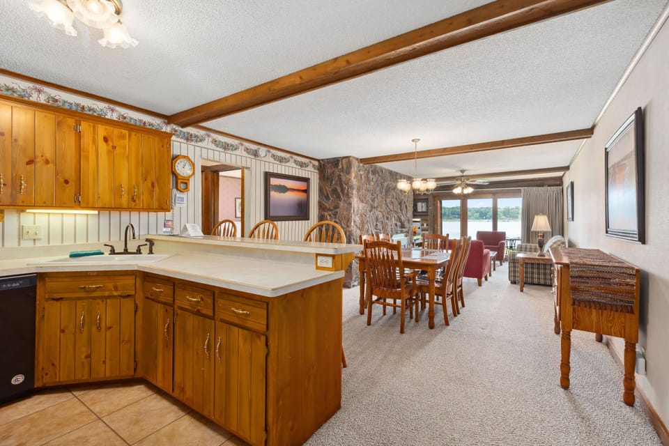 Fully equipped kitchen with wood cabinetry and breakfast bar next to the dining area.