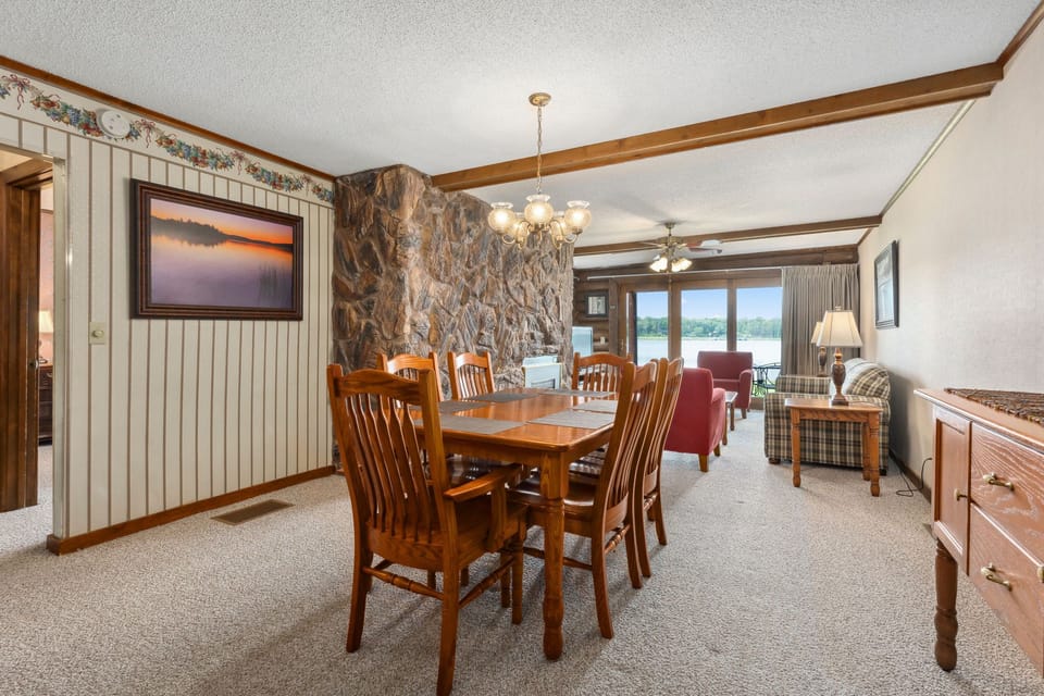 Bright dining space with wooden table and stone accent wall, opening to the living room.