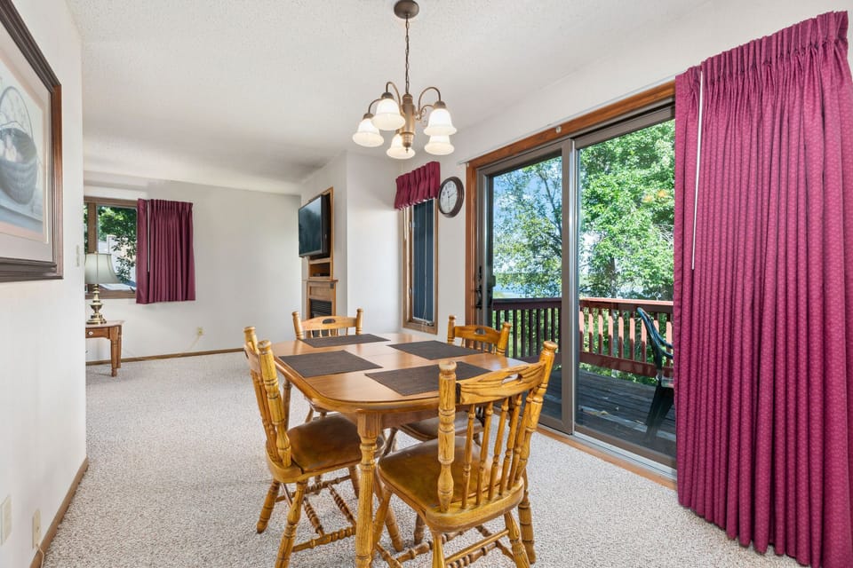 Open dining space with wooden table and balcony access through sliding doors.