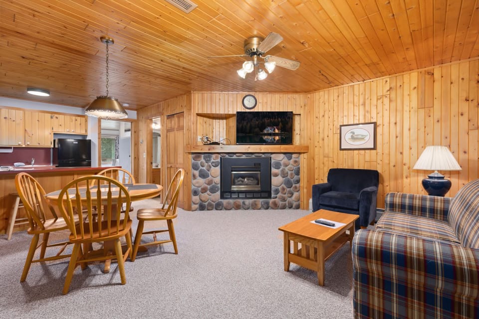 Spacious living and dining area with stone fireplace, dining set, and cozy seating.
