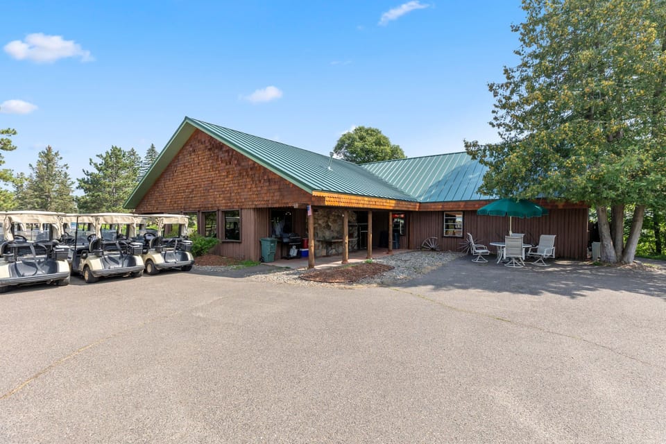 Clubhouse exterior with shaded entry and golf carts nearby.