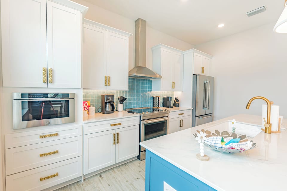 Bright and stylish kitchen with gold hardware, rich blue tile backsplash, and a breezy coastal-boho design that feels both modern and relaxed.
