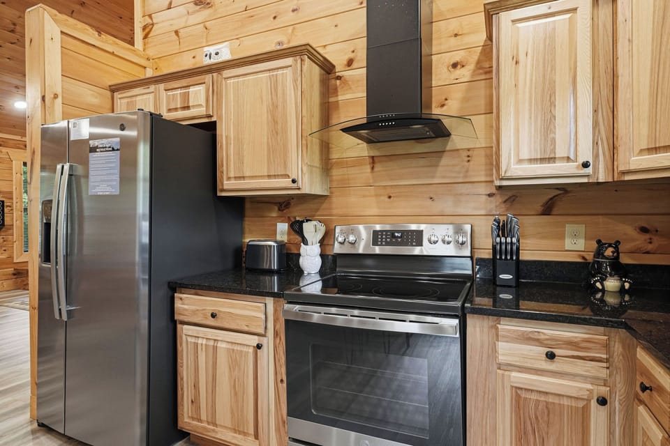 Your fully equipped cabin kitchen features sleek stainless-steel appliances, warm wood cabinetry, and stylish granite countertops—perfect for whipping up morning coffee or a hearty family meal together.