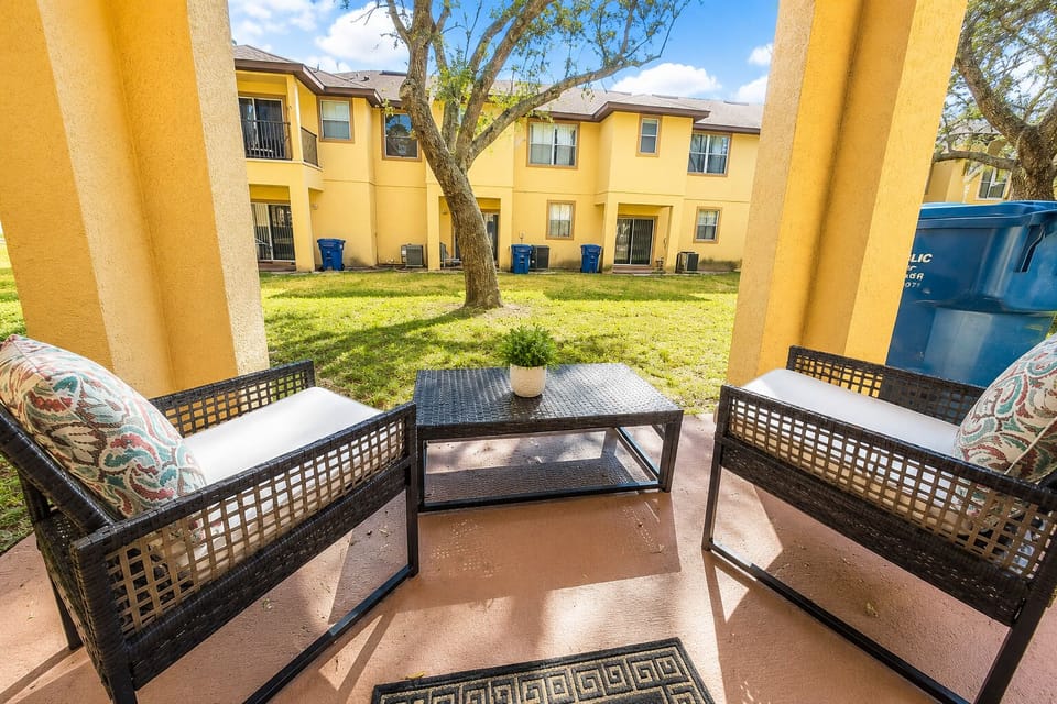 Covered patio with outdoor seating and a peaceful courtyard view — a nice spot to enjoy morning coffee, fresh air, or a quiet break between park and resort activities.