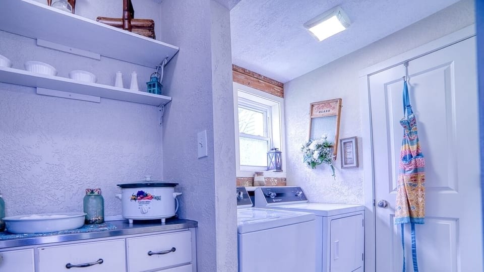 Laundry room equipped with washer, dryer, ironing board, iron and more. 