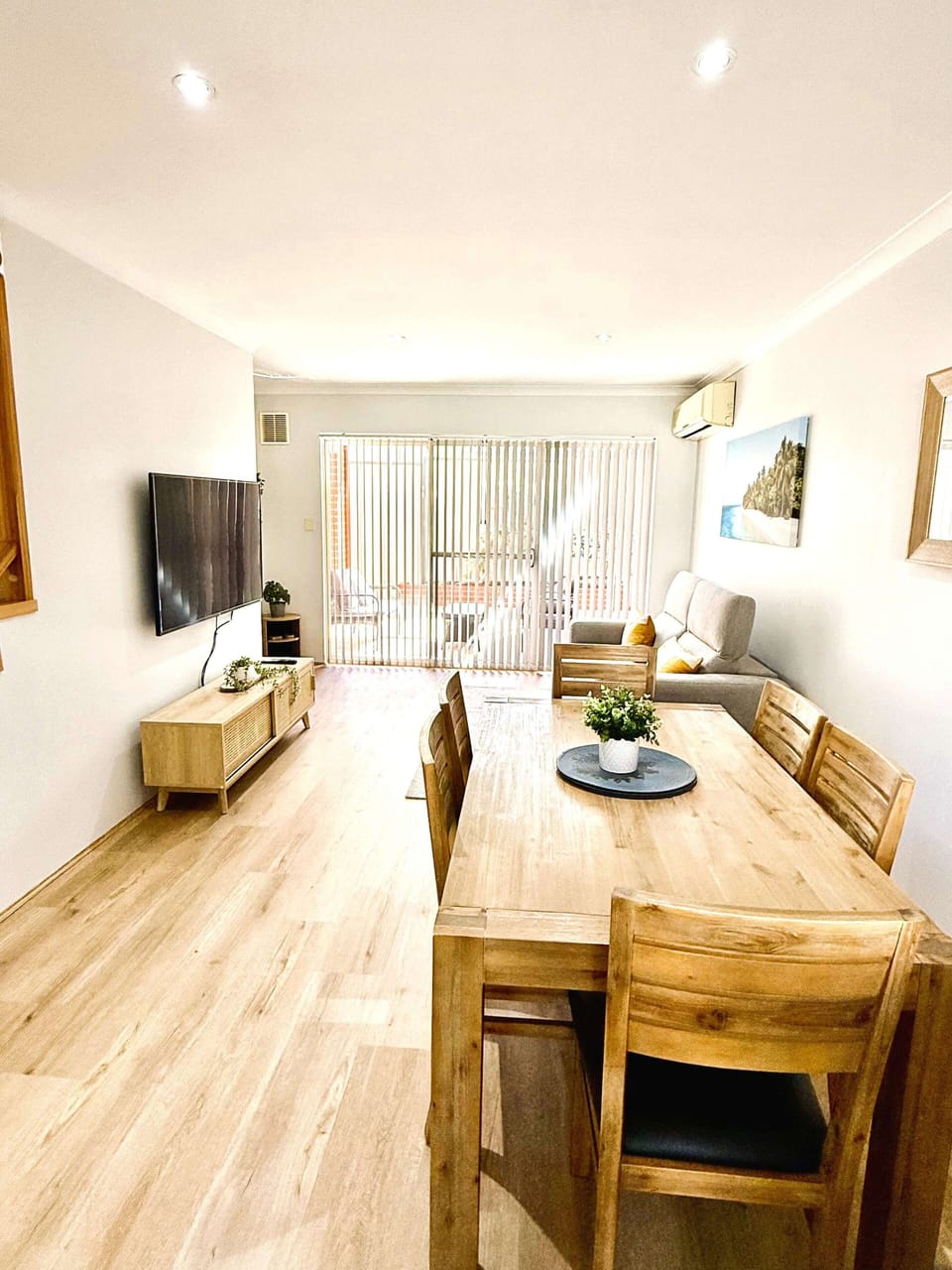 This air-conditioned apartment features an open-plan living and dining area with a cozy sofa, a modern flat-screen TV, and a wooden dining table that comfortably seats 4, creating a perfect space for unwinding and enjoying meals.