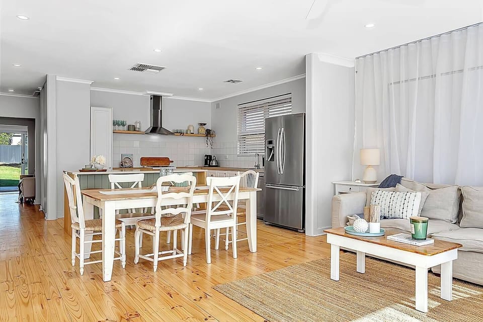 Gather around the country-style dining table that seamlessly connects the kitchen and living area—a welcoming area for shared meals and conversation.