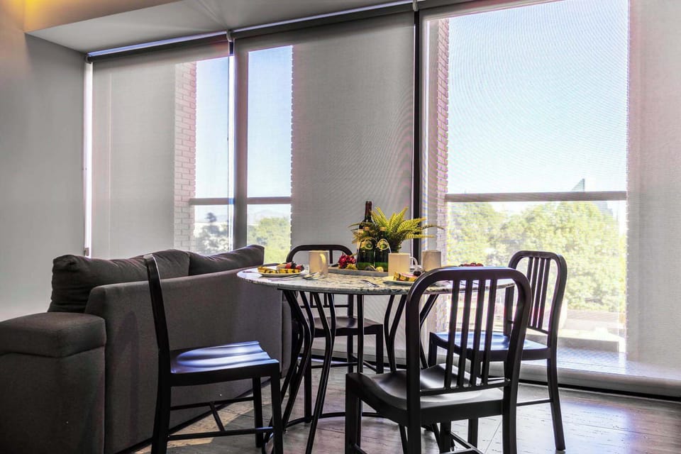 Dining table set by large windows, a bright spot for meals w/ city views