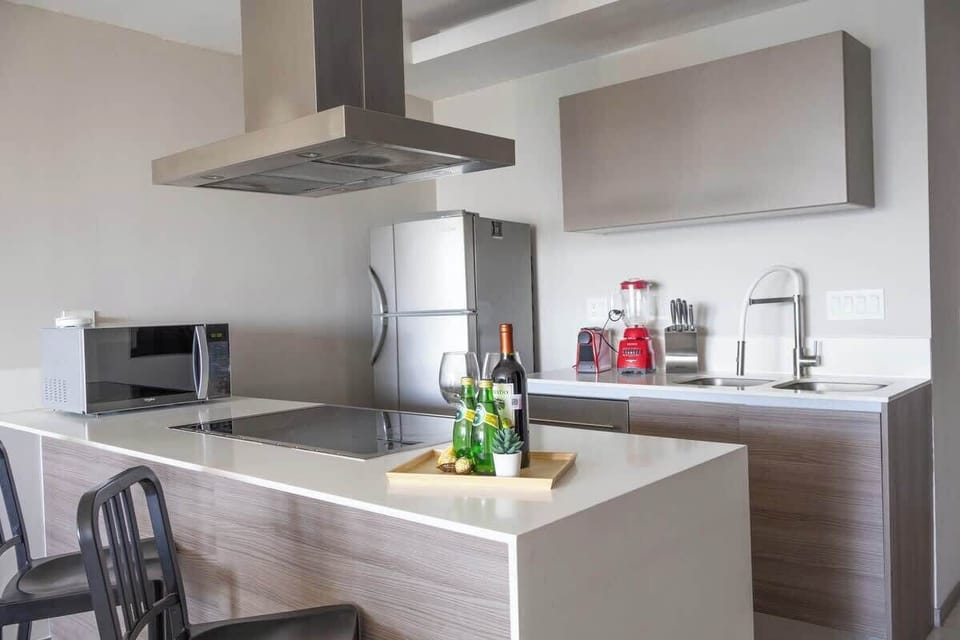Modern kitchen w/ sleek counters, island seating & stainless hood for easy meal prep