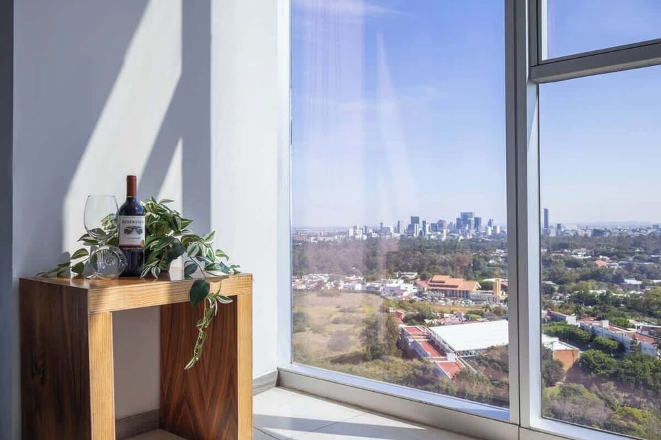 Window nook w/ chair & table beside floor-to-ceiling glass showcasing city views