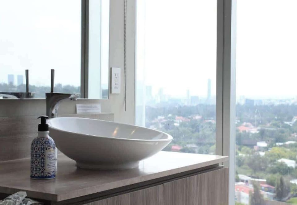 Modern bathroom sink set by a large window, offering panoramic city skyline views