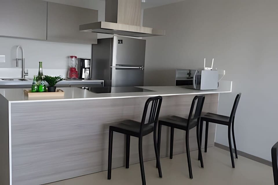 Sleek kitchen bar w/ stools & stainless range hood for easy breakfasts or evening drinks