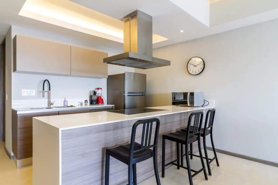 Modern kitchen w/ island seating, sleek cabinets & stainless range hood