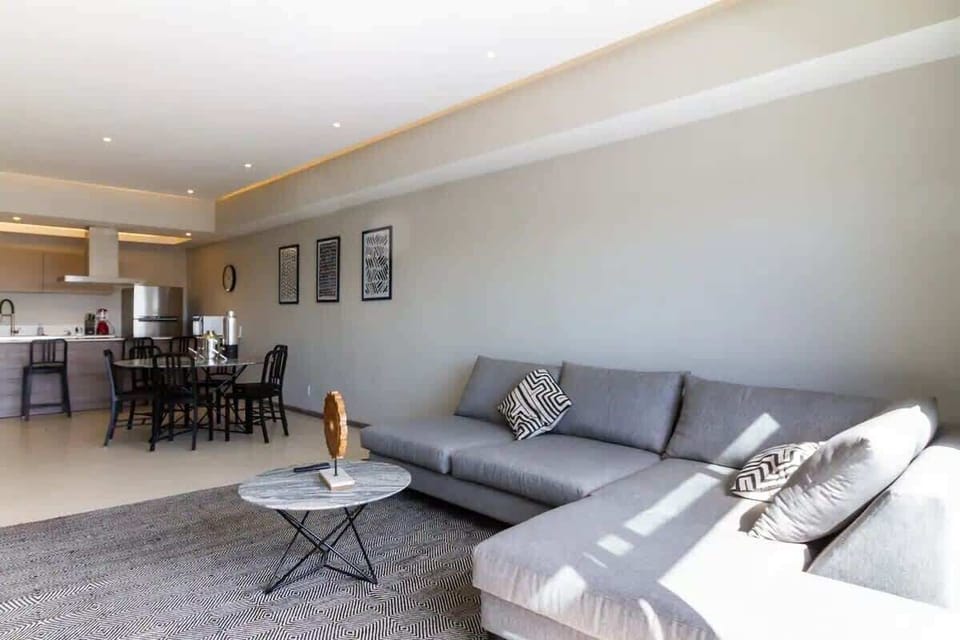 Bright living room w/ comfy sofa seating, TV & wide windows bringing in natural light