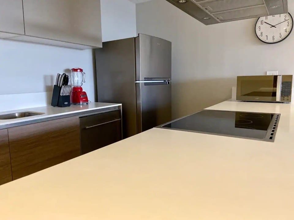 Sleek kitchen counter space w/ sink, modern cabinets & stainless appliances