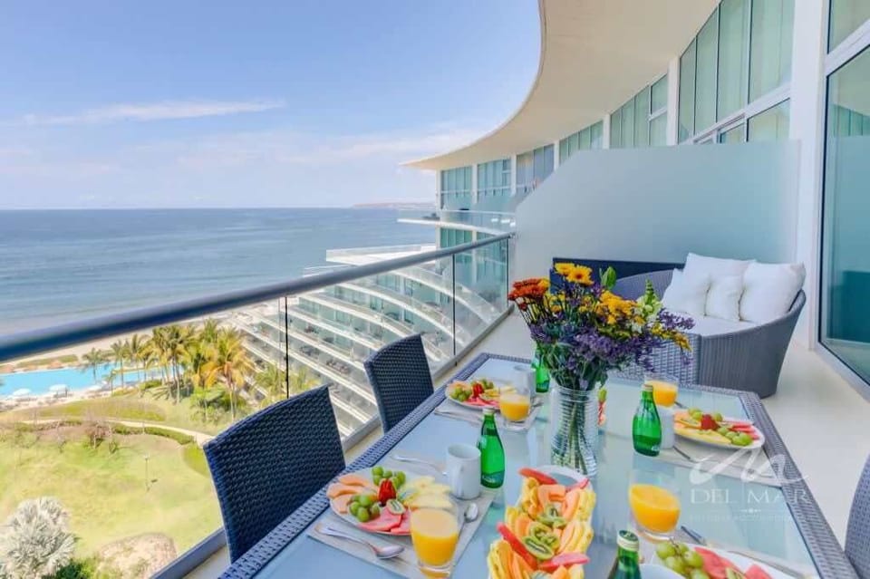 Balcony dining table set for a meal w/ sweeping ocean views stretching along the coast