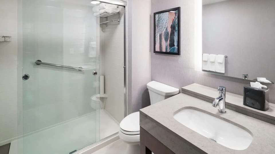 Refresh in a spotless bath with glass shower and bright vanity.
