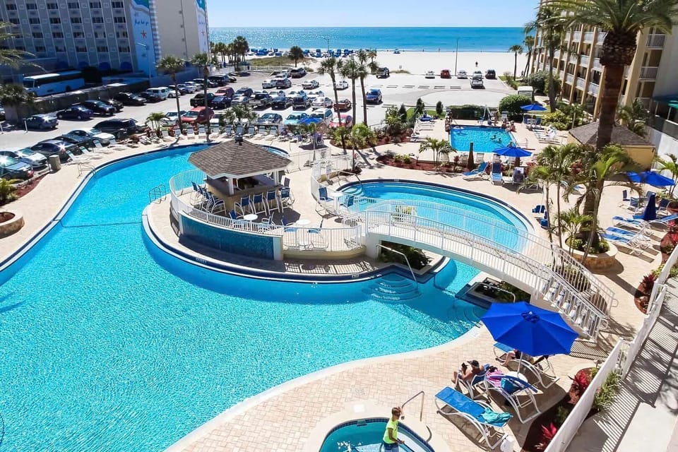 Discover the inviting pool area complete with a waterfall and a connecting bridge while enjoying direct beach access, perfect for family fun and relaxation.