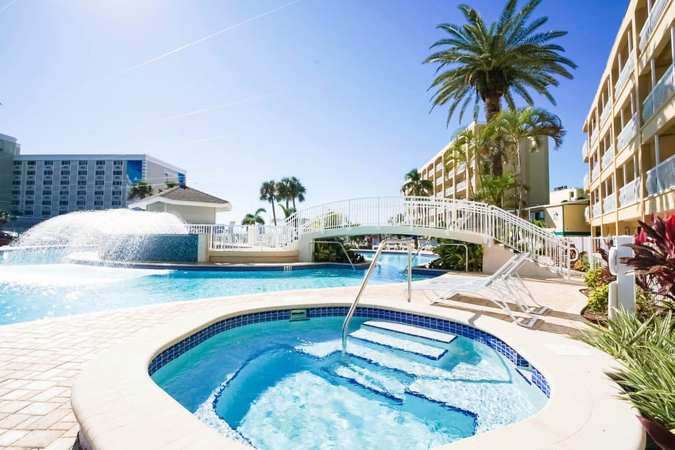 Relax in the inviting hot tub near the outdoor pool, set against a backdrop of palm trees and inviting loungers in this vibrant condo community.