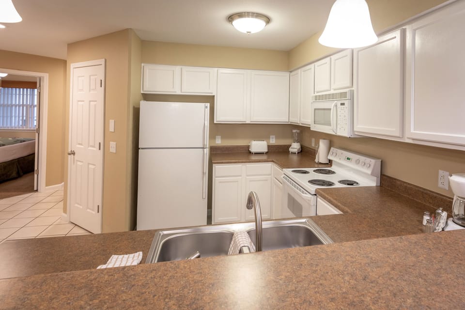 Bright kitchen with white cabinetry, stove, dishwasher, and toaster — fully stocked for your stay