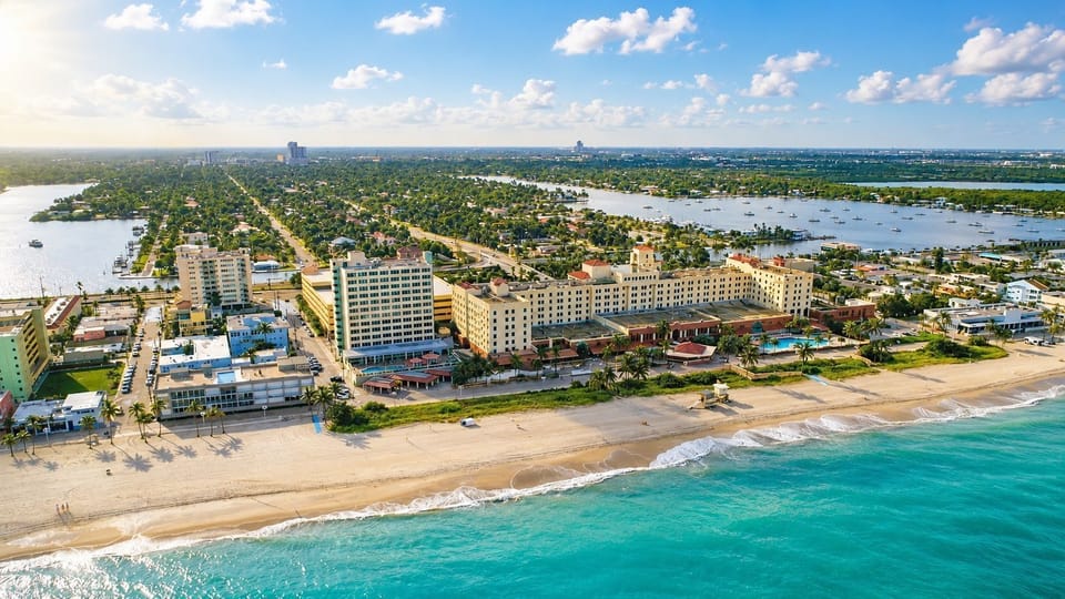 Aerial view of beach, buildings, and waterways with boats