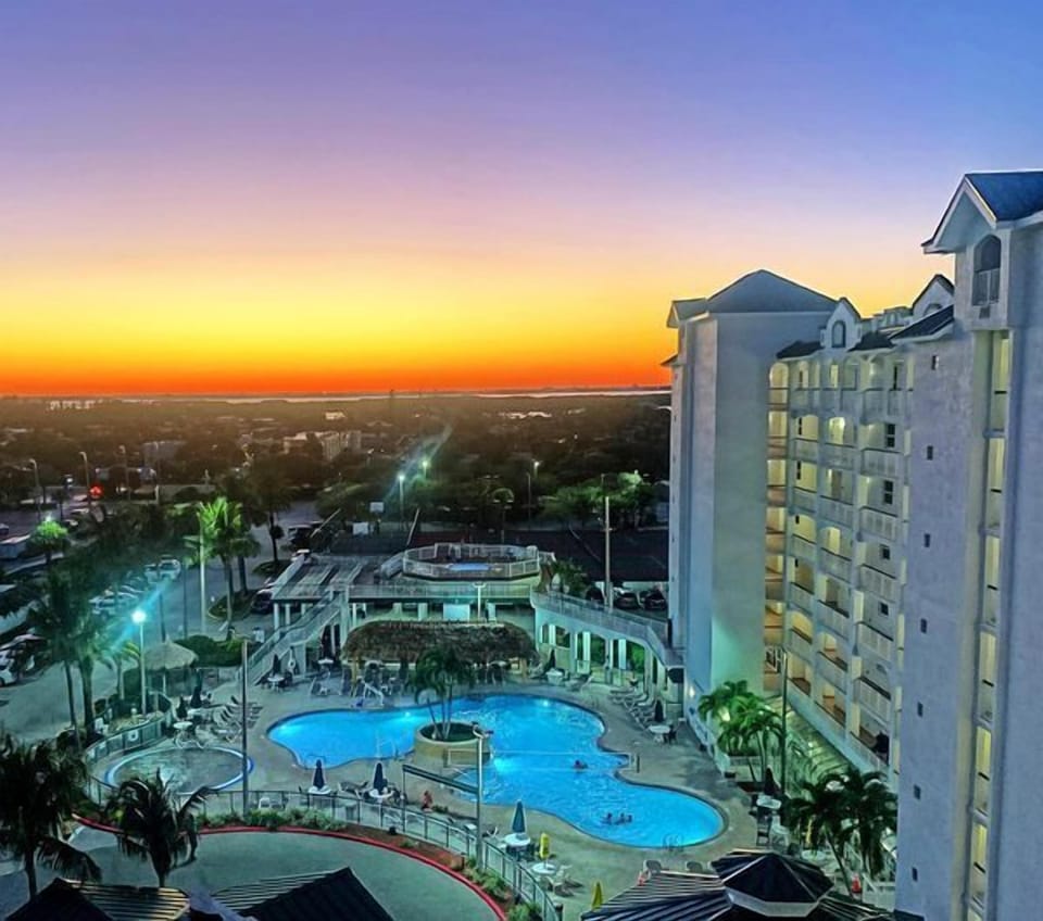 Bask in the stunning sunset from the luxurious pool area, surrounded by palm trees and serene waters.