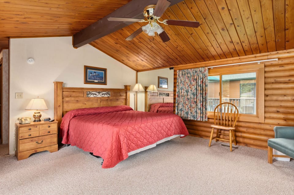 Another angle of the bedroom showing its spacious interior with wood ceilings, red bedding, and plenty of natural light.