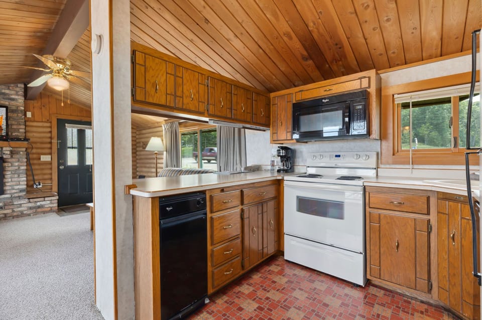 Fully equipped kitchen with wooden cabinetry, stove, and large window view.