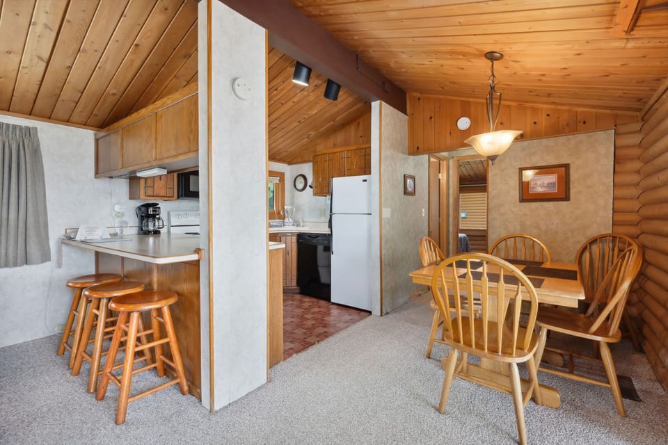 Quaint dining area with round wooden table set beside the kitchen.