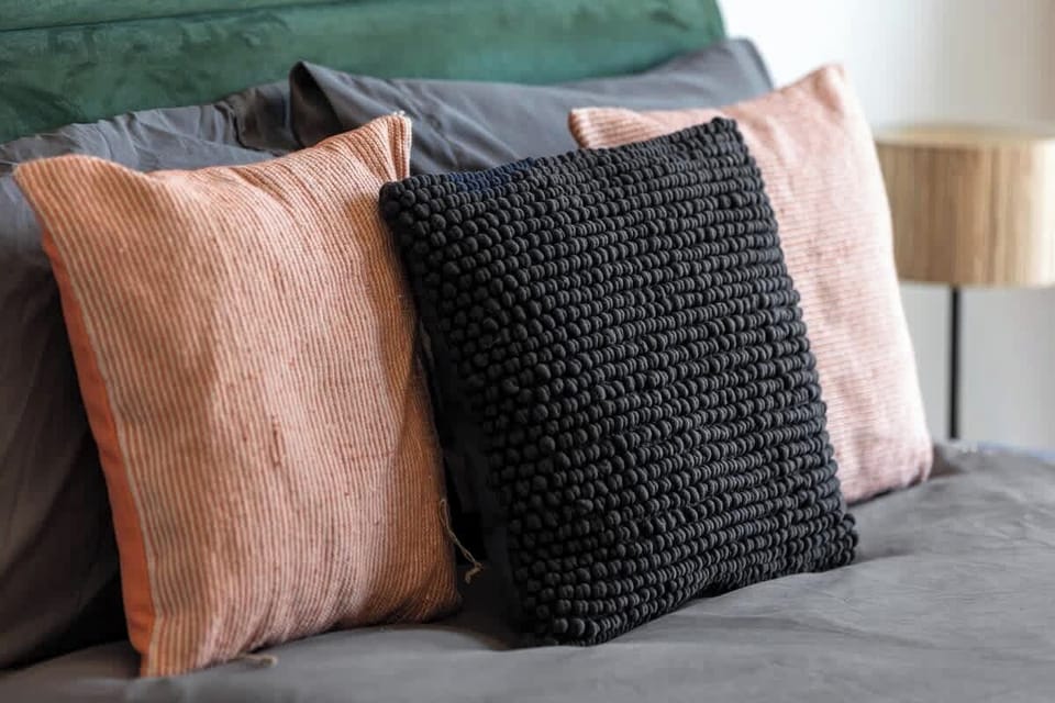 - Plush bedding with cozy accent pillows in warm earthy tones  
- Soft textures add comfort and style to the Airbnb bedroom  
- Perfectly designed setup for restful and peaceful nights  