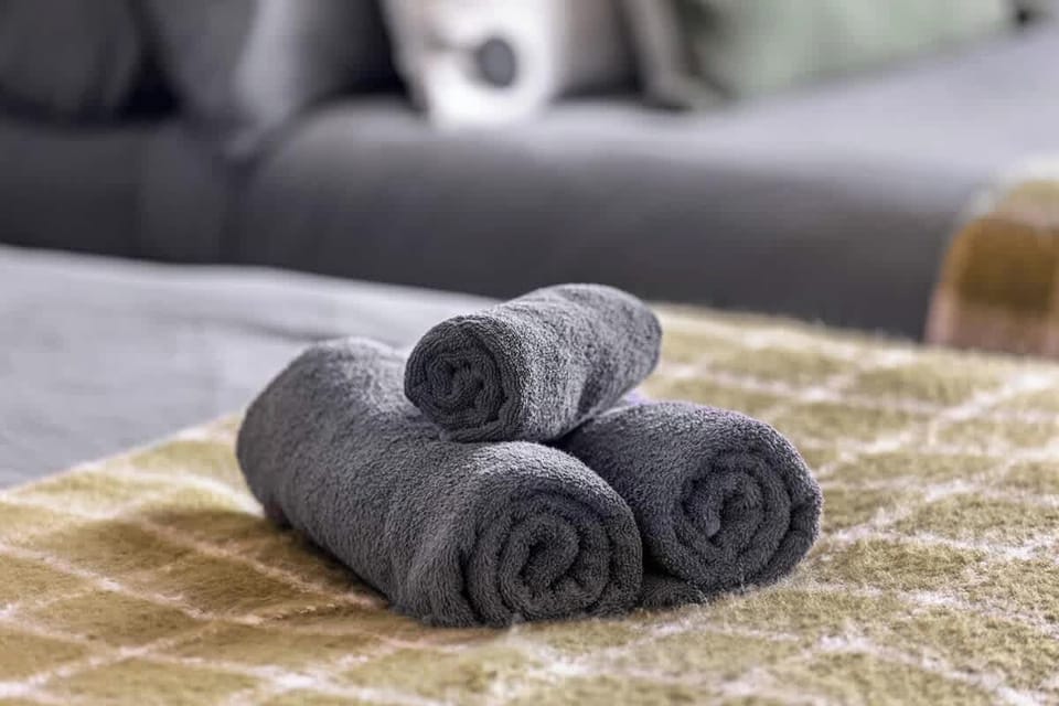 - Freshly rolled towels arranged neatly on soft patterned throw  
- Guest essentials prepared with care for every Airbnb booking  
- Cozy touches ensure comfort and hospitality during stays  
