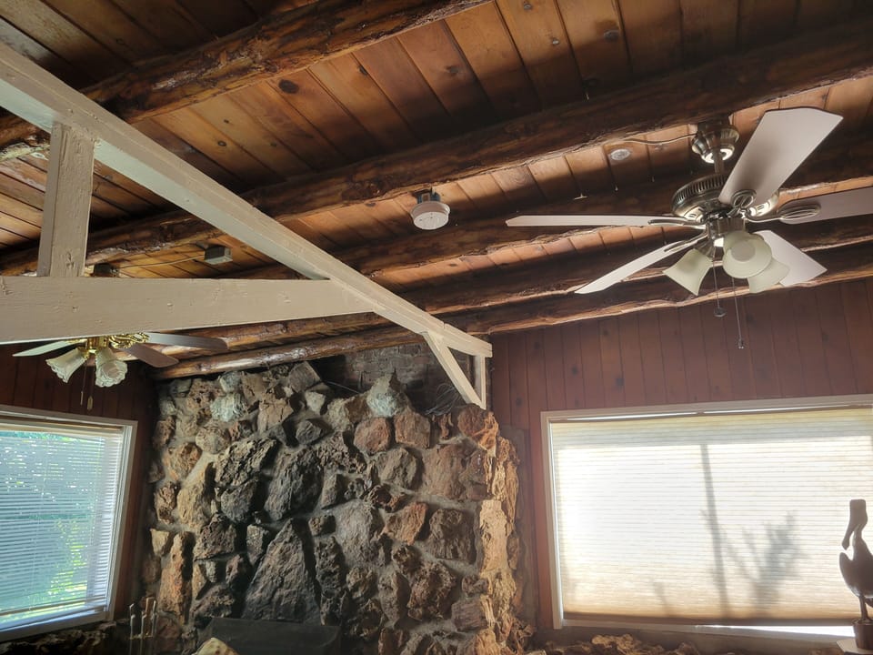 Cabin ceiling with fans, that is a fireplace in the corner