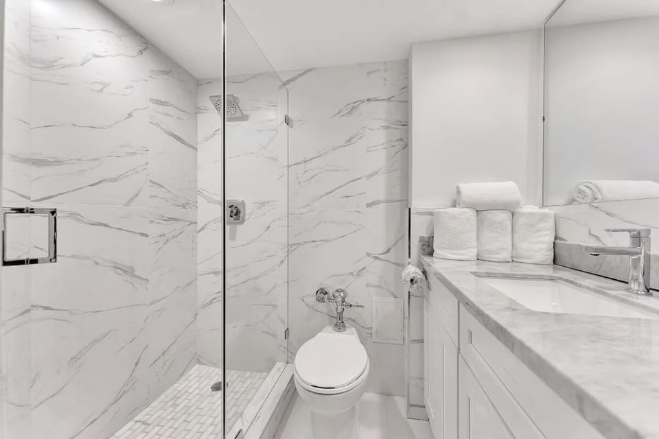 Refresh in a sleek marble-style bath with glass shower.