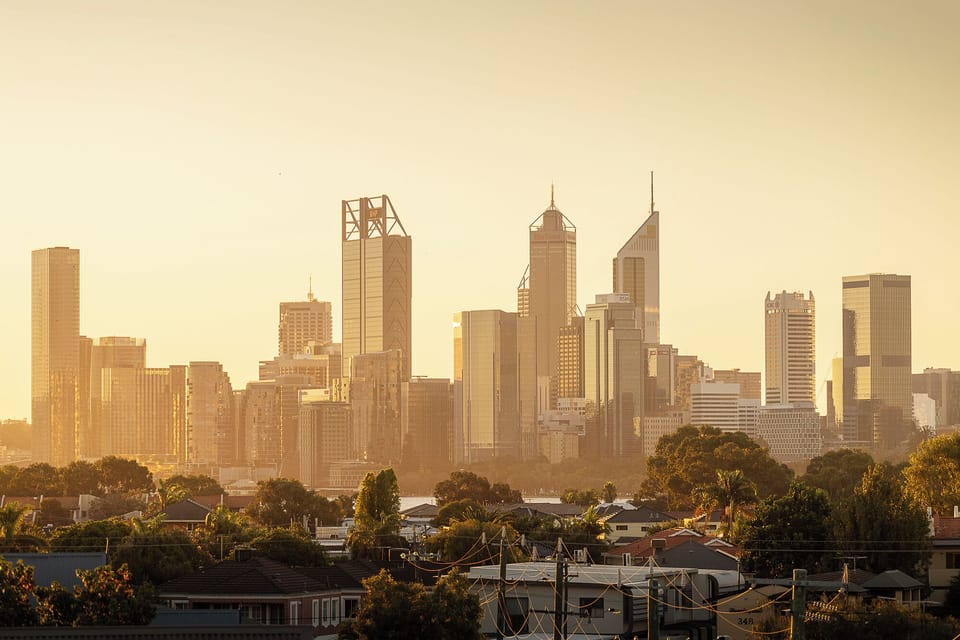 Witness a stunning sunset over the city skyline, where buildings are silhouetted against an orange-hued sky, creating a dramatic and beautiful urban landscape.