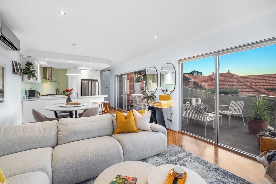 Extend your living space outdoors with a comfortable living area featuring a large sectional sofa and decor, seamlessly connected to a patio through wide sliding doors, providing a perfect spot for indoor-outdoor enjoyment.