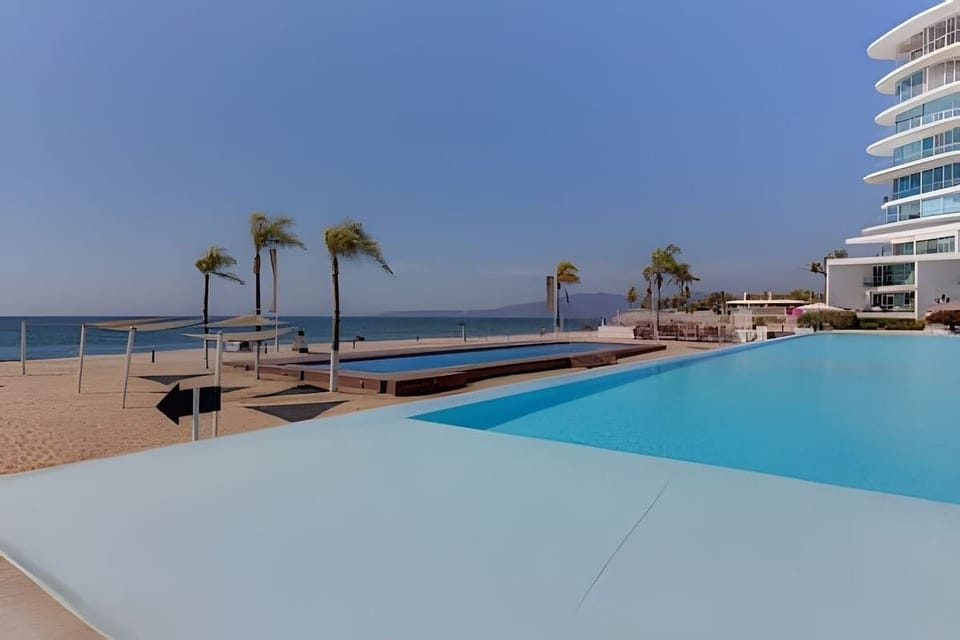 Shared infinity pool w/ palm trees & ocean views stretching to the horizon