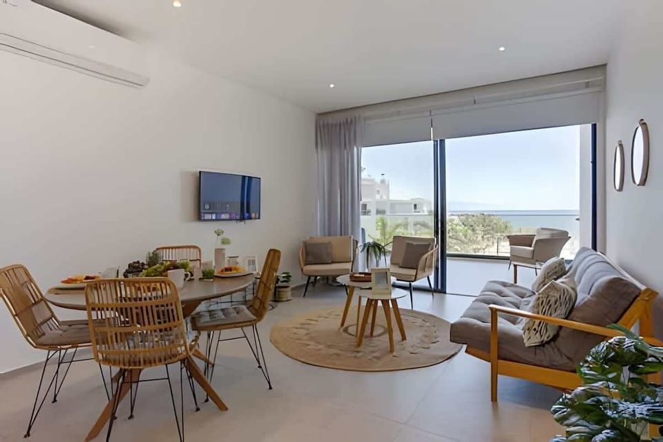 Bright living & dining space w/ comfy sofa, round table & balcony doors welcoming natural light