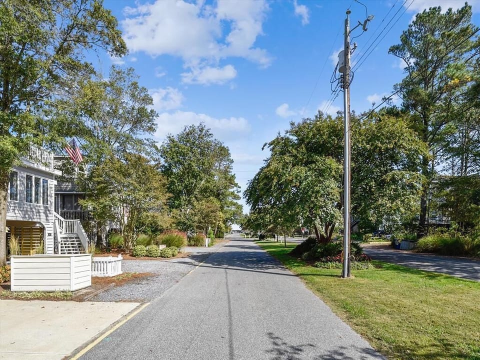 A serene street view lined with mature trees offers a glimpse of the peaceful surroundings, showcasing the rental's proximity to quaint shops and the idyllic atmosphere of Bethany Beach.