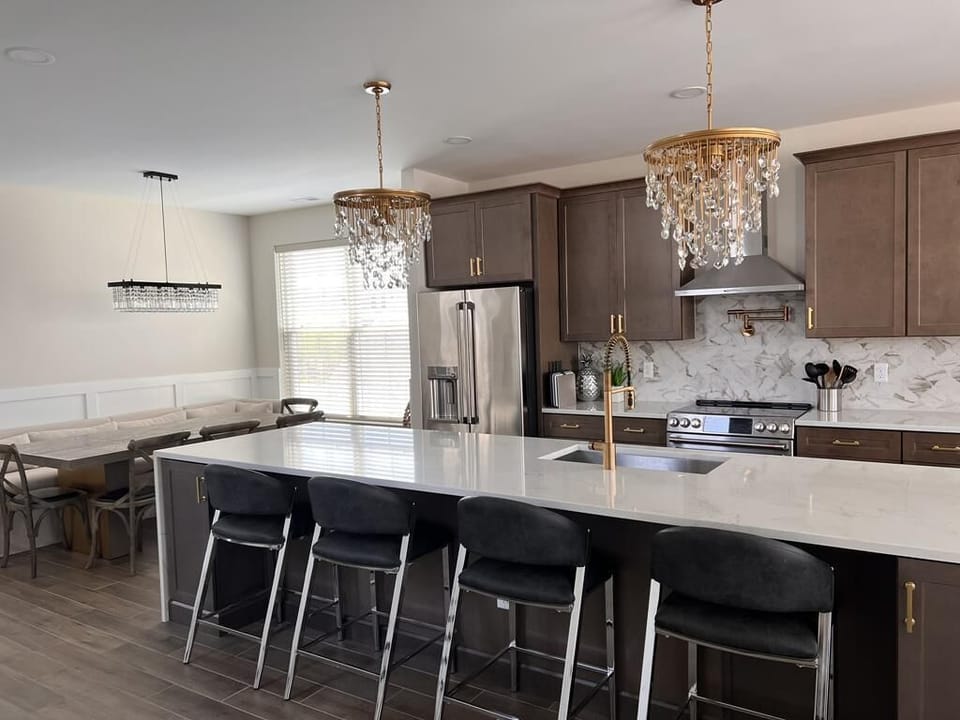 A chef’s dream kitchen featuring a massive island, high-end appliances, and elegant chandeliers.