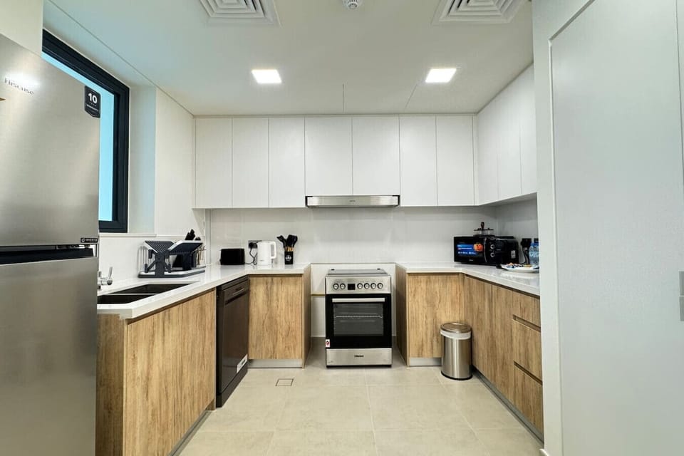 This modern U-shaped kitchen combines sleek white upper cabinets with warm wood-grain lower cabinets, creating a perfect balance of contemporary style and natural warmth.